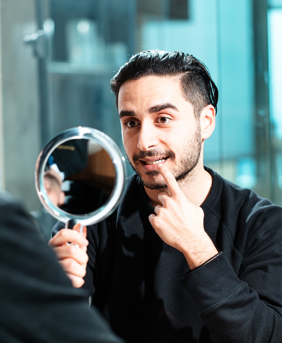 Male patient looking at teeth in a mirror.